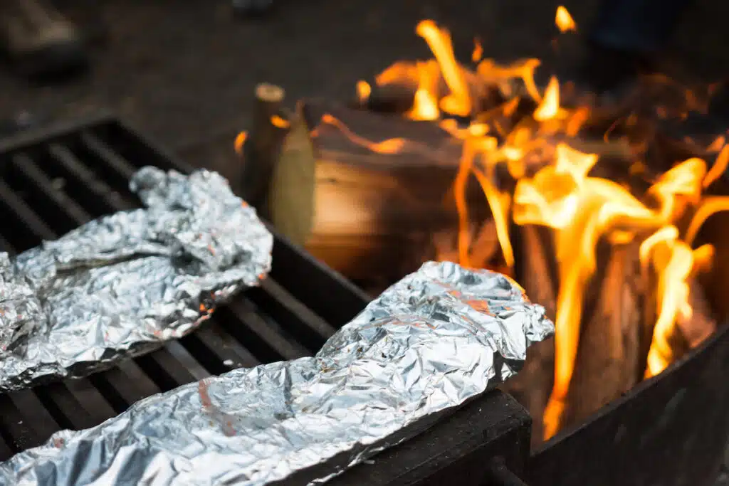 tin foil hobo packets on campfire grate over fire