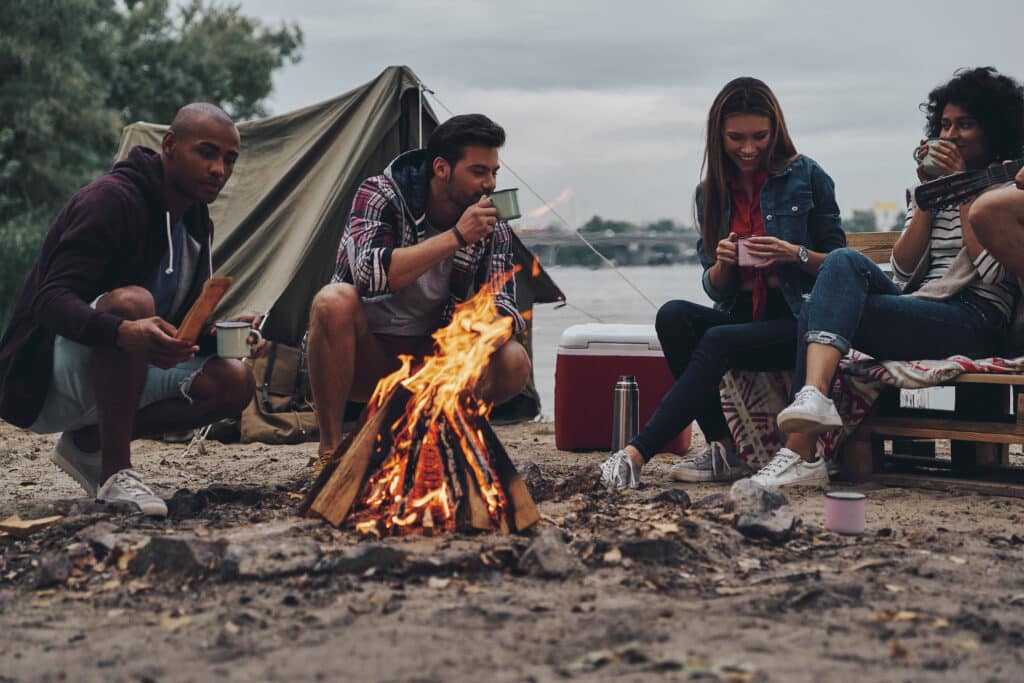 People sitting next to campfire and tent