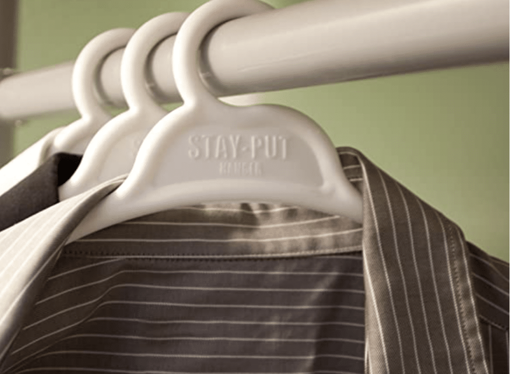 white plastic hanger with brown shirt on clothes rod