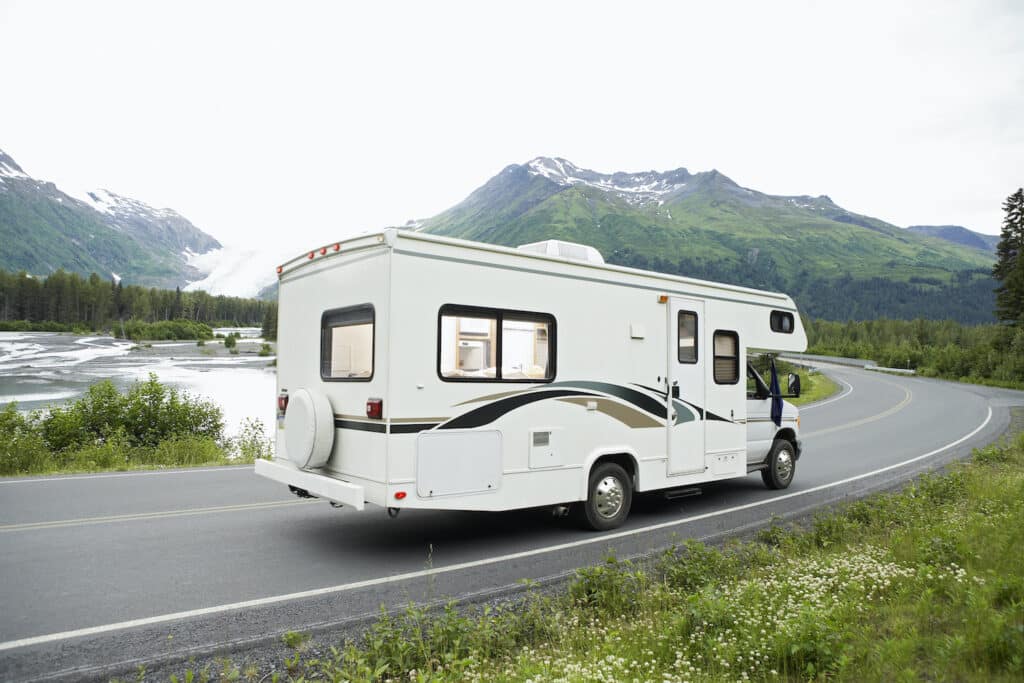 camper trailer driving on road with mountains in background