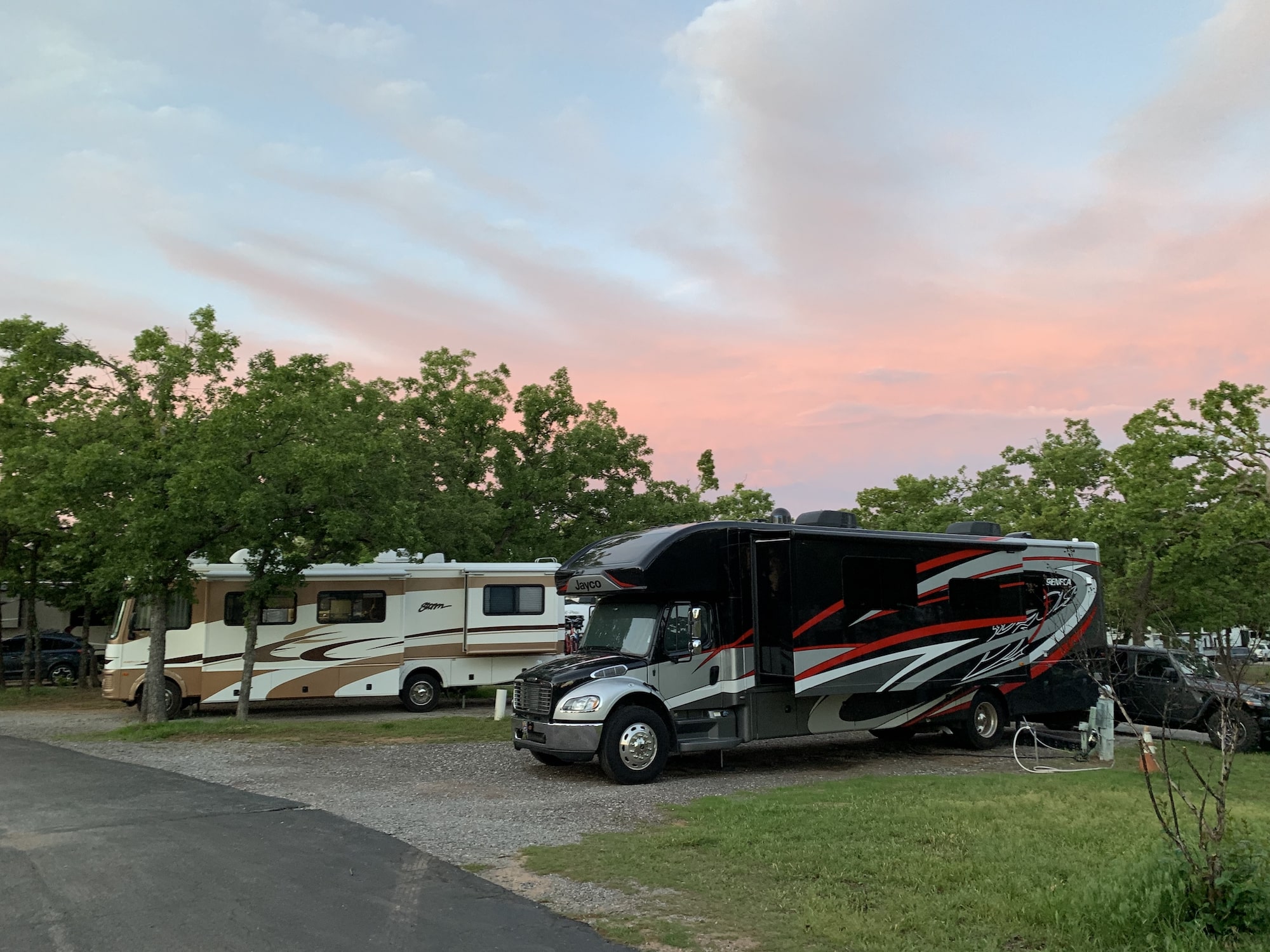motorhome RVs parked in campground campsites with sunset in sky behind