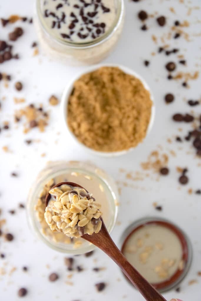 Cookie Dough Overnight Oats in wooden spoon over white table with chocolate chips