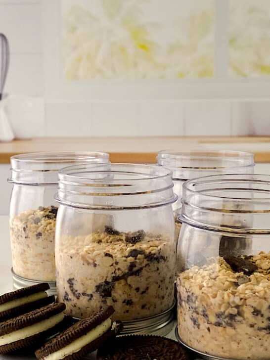Cookies N Creme Overnight Oats in small jars with Oreo cookies on countertop