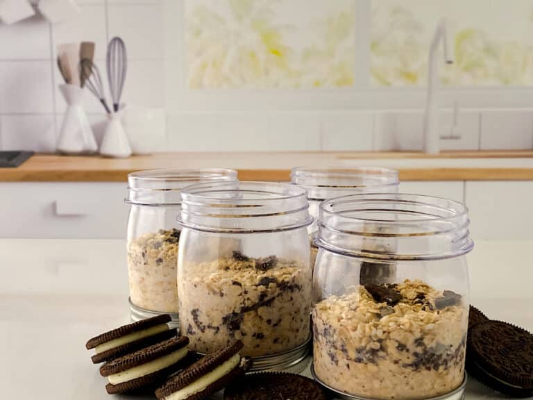 Cookies N Creme Overnight Oats in small jars with Oreo cookies on countertop