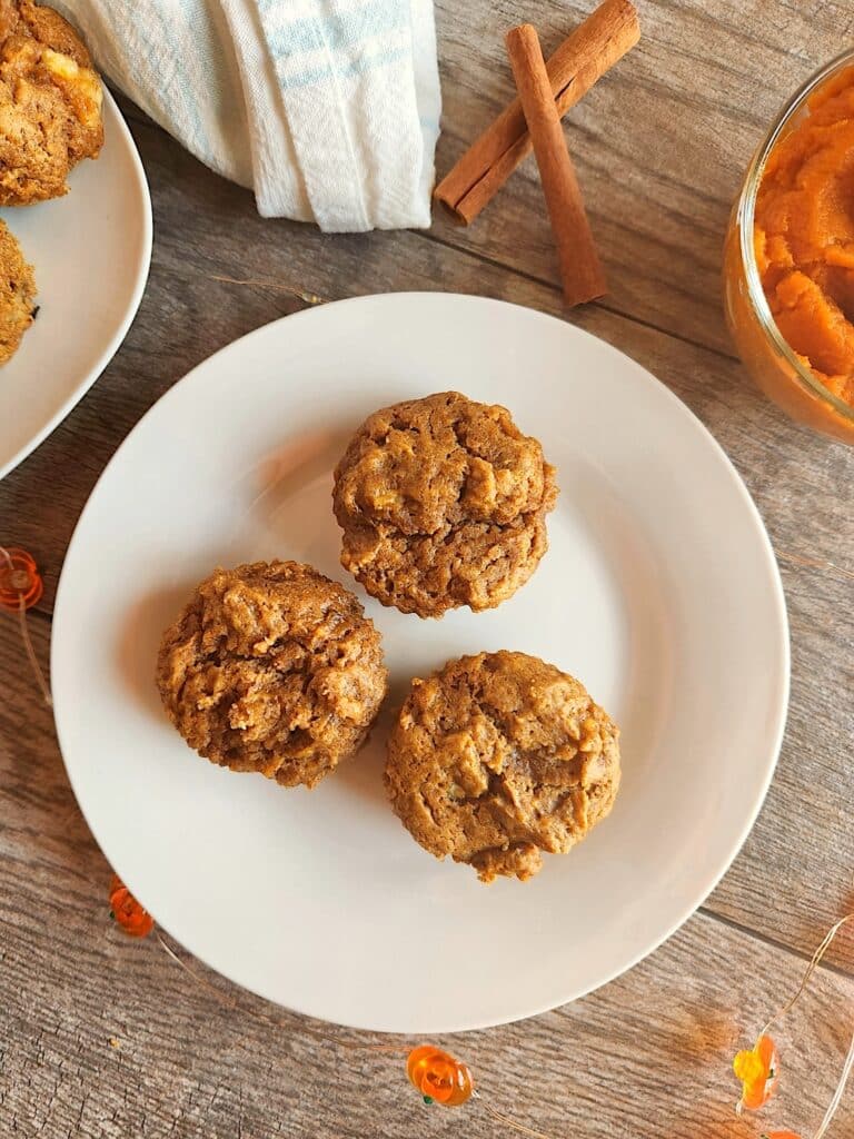 Pumpkin Banana Muffins on white plate sitting on wood plank table top