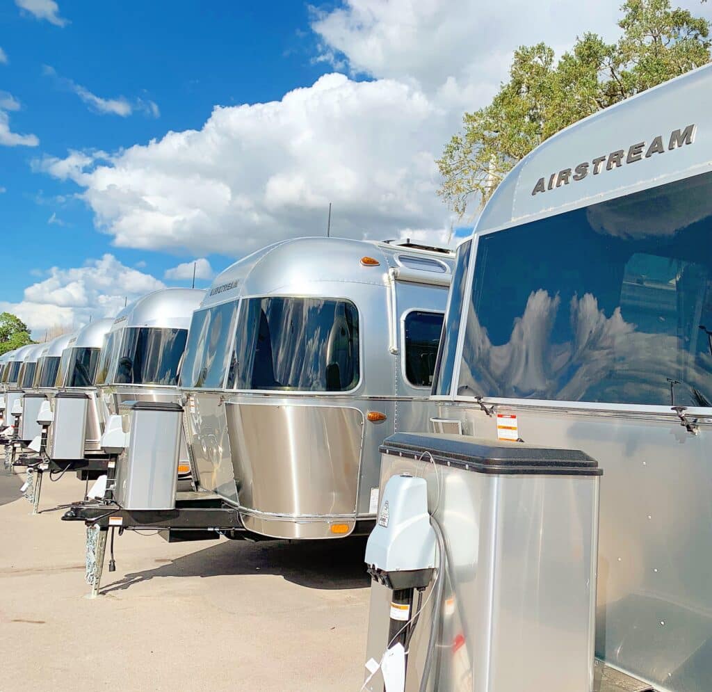 line of silver airstream res underneath blue sky with clouds