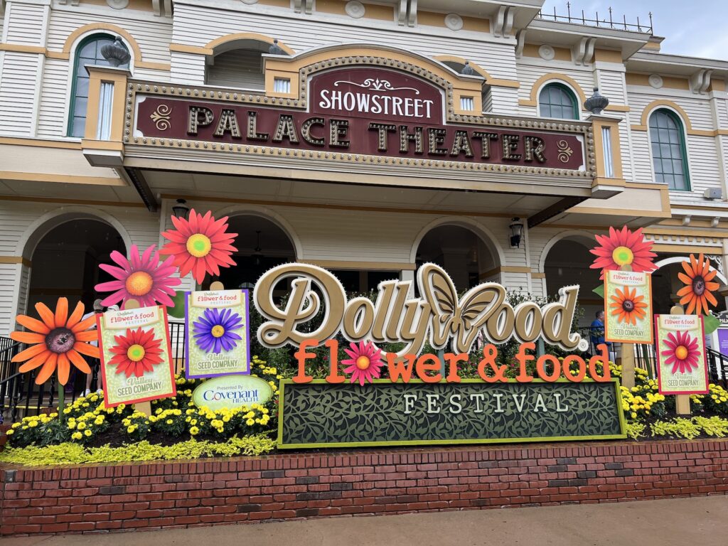 Entrance to the Dollywood Flower & Food Festival with vibrant floral decorations and a Dollywood sign in front of the Showstreet Palace Theater.