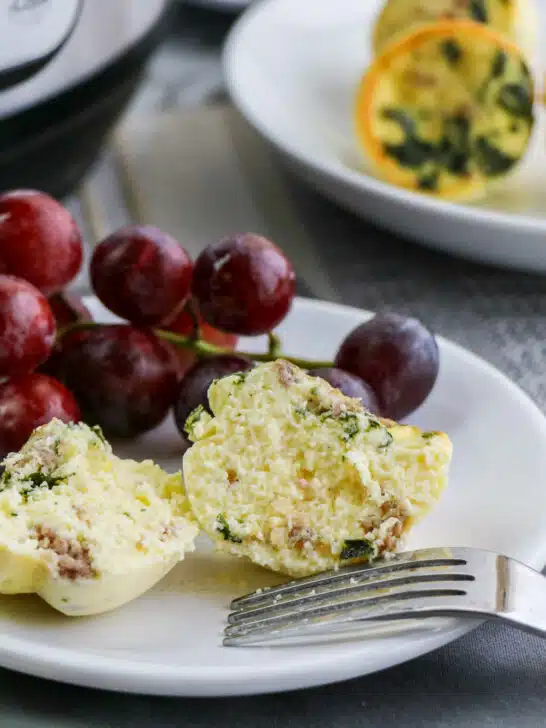 small sous vide egg bites on a white plate with red grapes and a fork in front of an Instant Pot