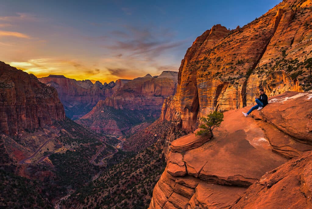 Tourist sitting at the Canyon Overlook in Zion National Park, Utah