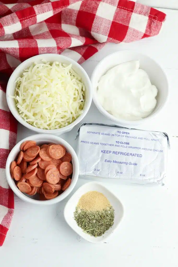 A bowl of cheese, peppers, and other ingredients on top of a red and white checkered tablecloth.