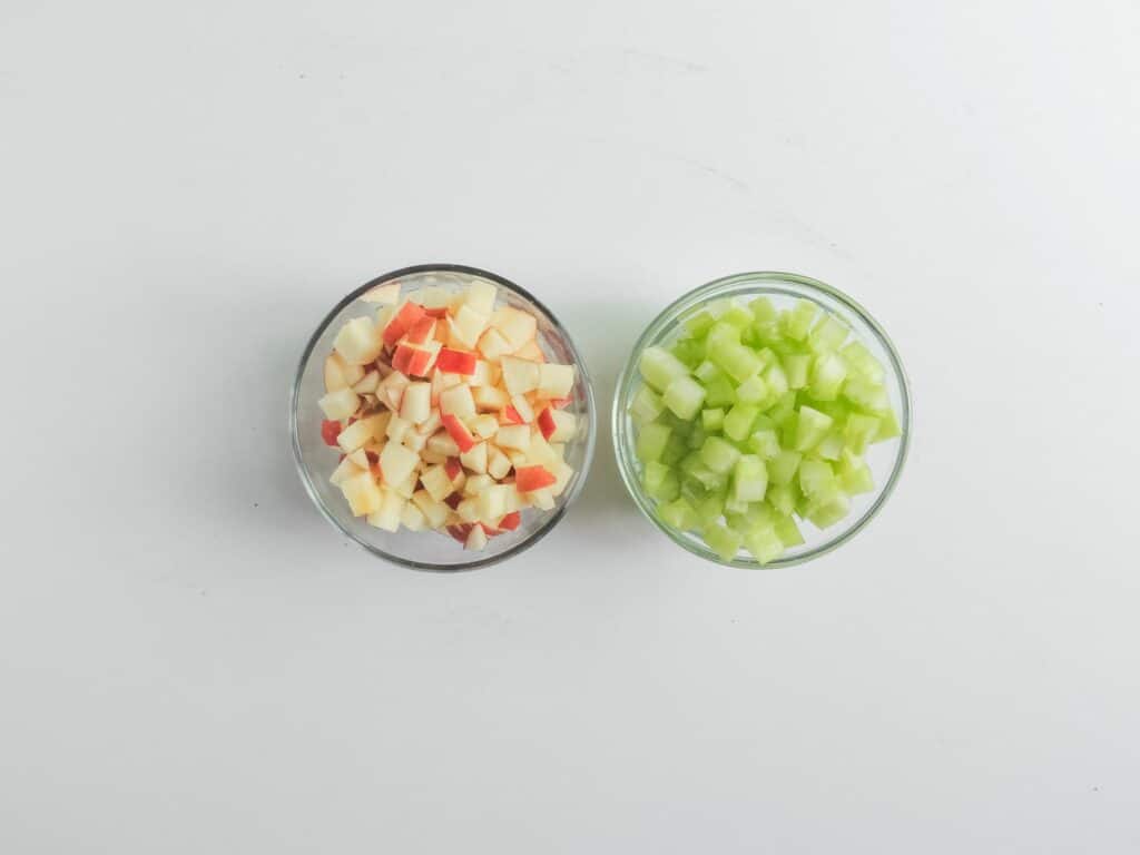 Two bowls of chopped celery and carrots on a white background.