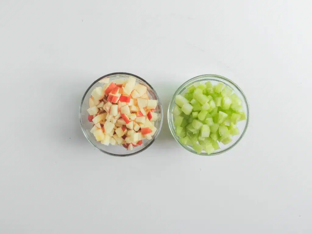 Two bowls of chopped celery and carrots on a white background.