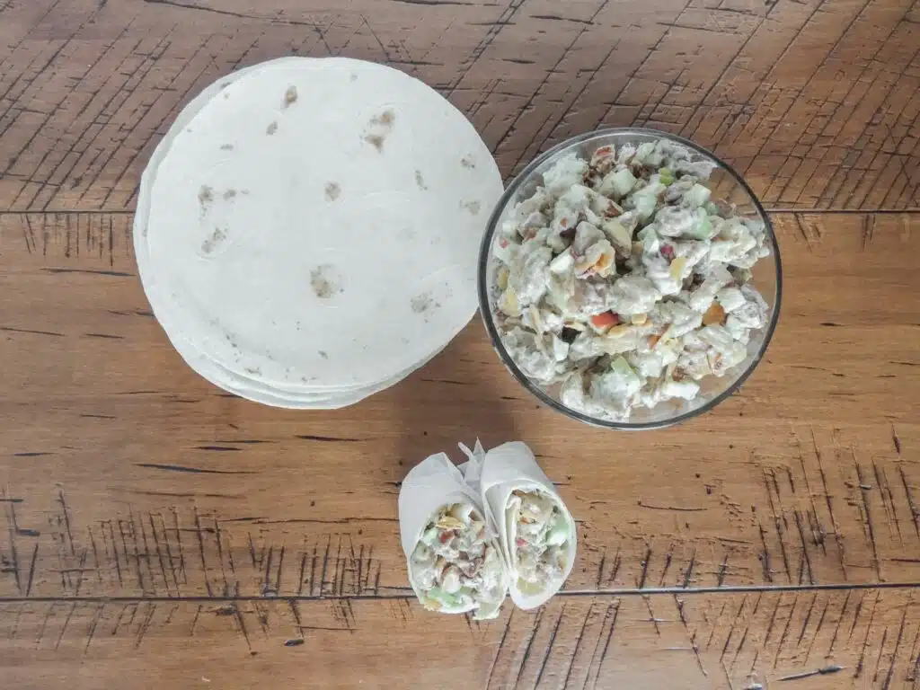 A bowl of salad and a tortilla on a wooden table.