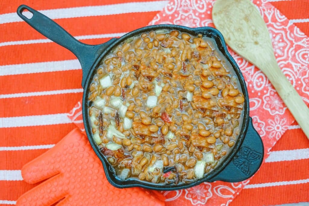 A skillet filled with beans and cheese on a red tablecloth.