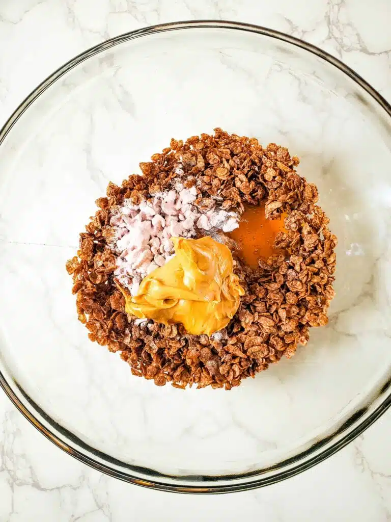 A glass bowl filled with granola and peanut butter.