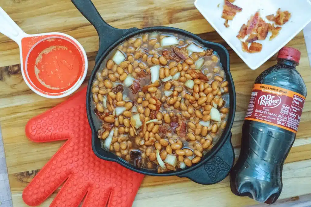 A skillet full of beans and a bottle of coca cola.