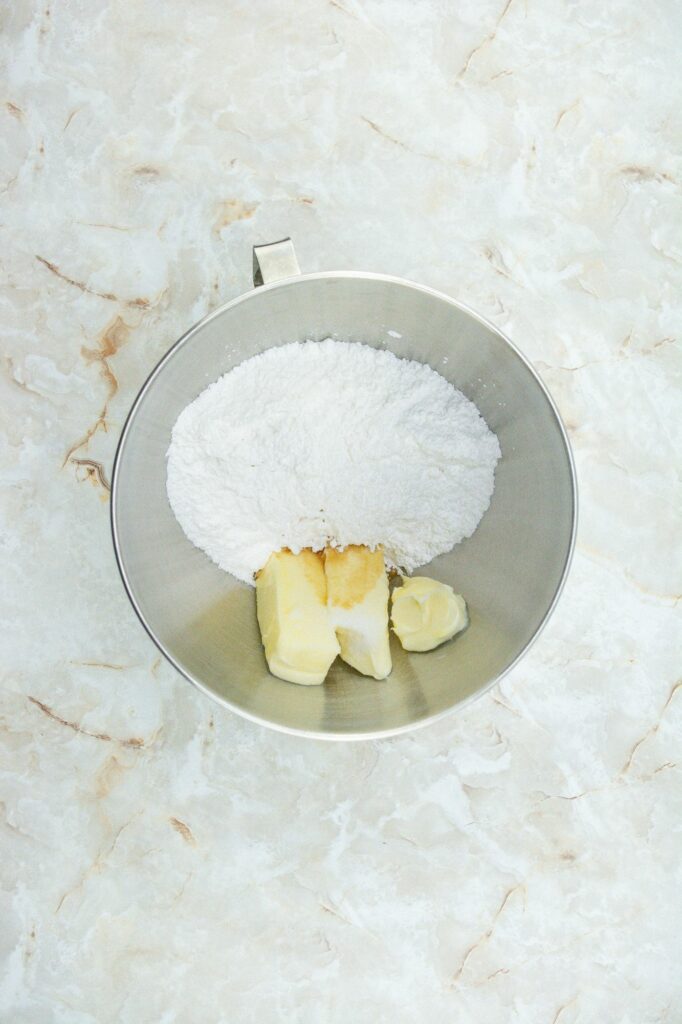 Flour and butter in a metal bowl on a marble surface.