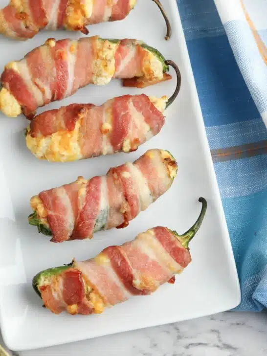Bacon wrapped jalapenos on a white plate.