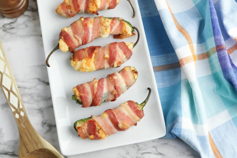Bacon wrapped jalapenos on a white plate.