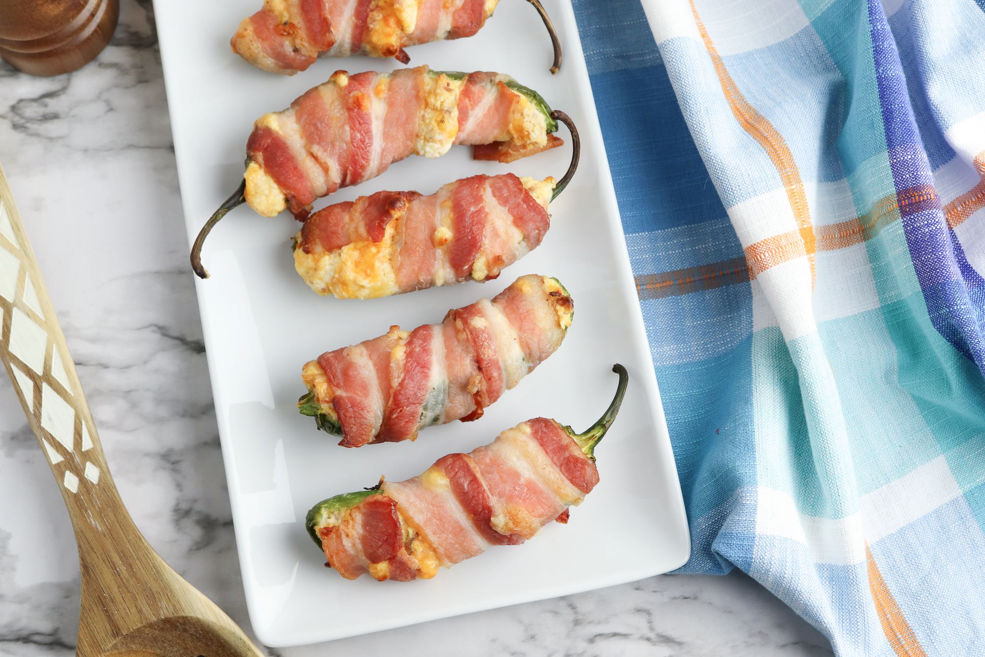Bacon wrapped jalapenos on a white plate.