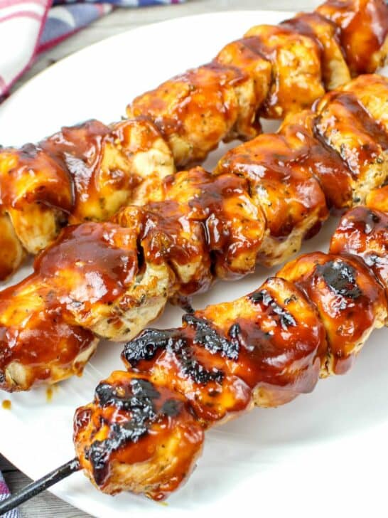 Bbq chicken skewers on a white plate.