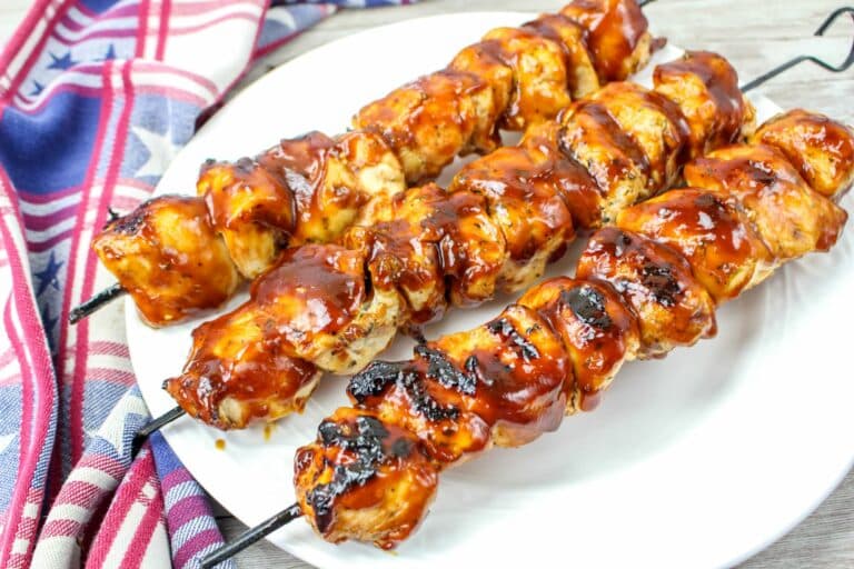 Bbq chicken skewers on a white plate.