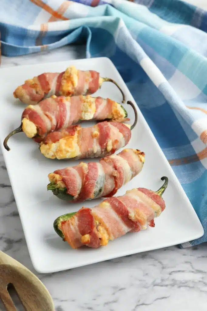 Bacon wrapped jalapenos on a white plate.