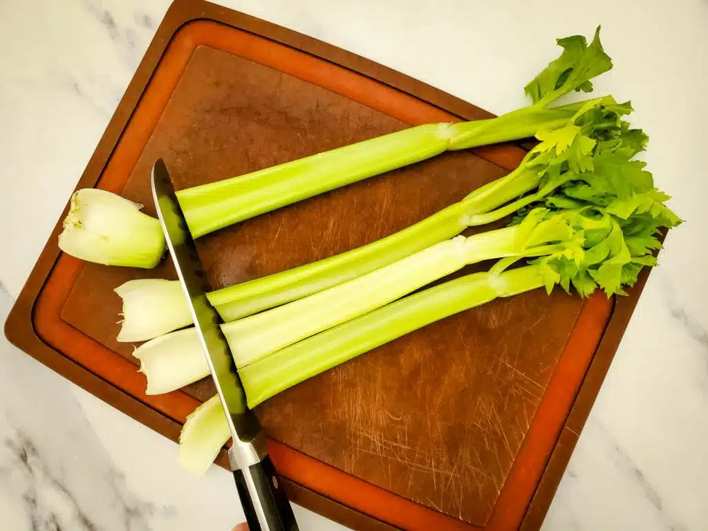 Celery on a cutting board with a knife.