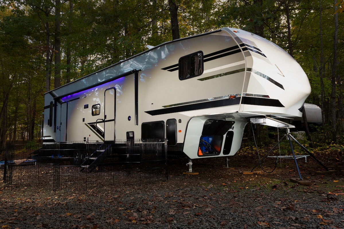 Fifth wheel trailer parked in a heavily wooded forest camp site