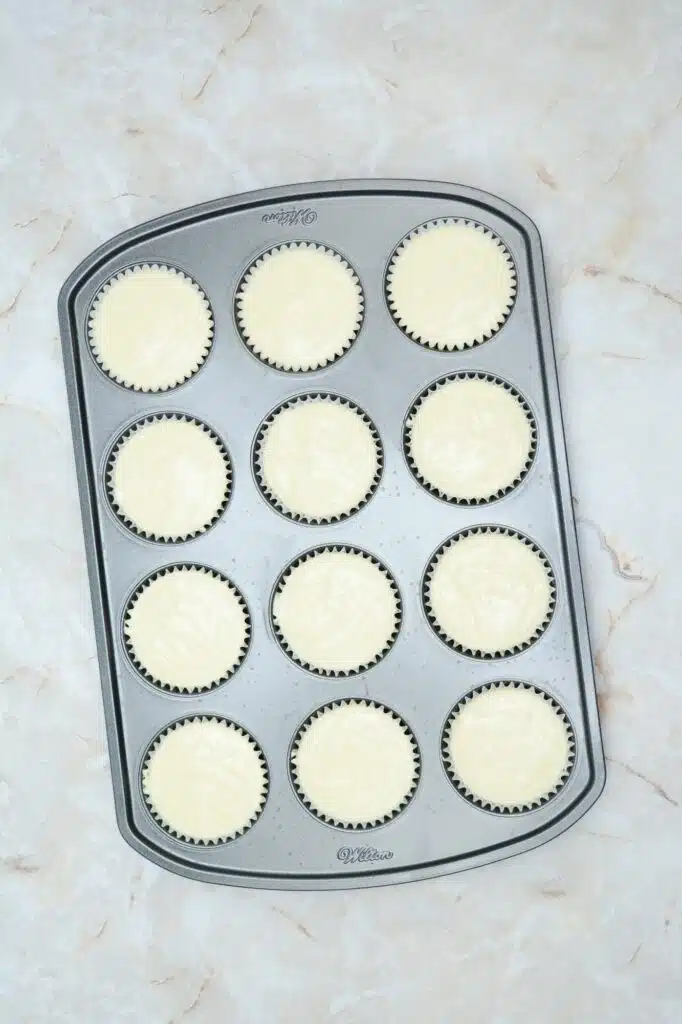 Cupcakes in a muffin pan on a marble countertop.