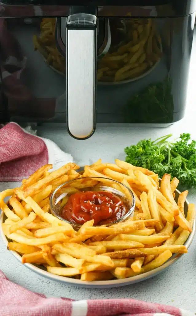 An air fryer with fries and ketchup on a plate.