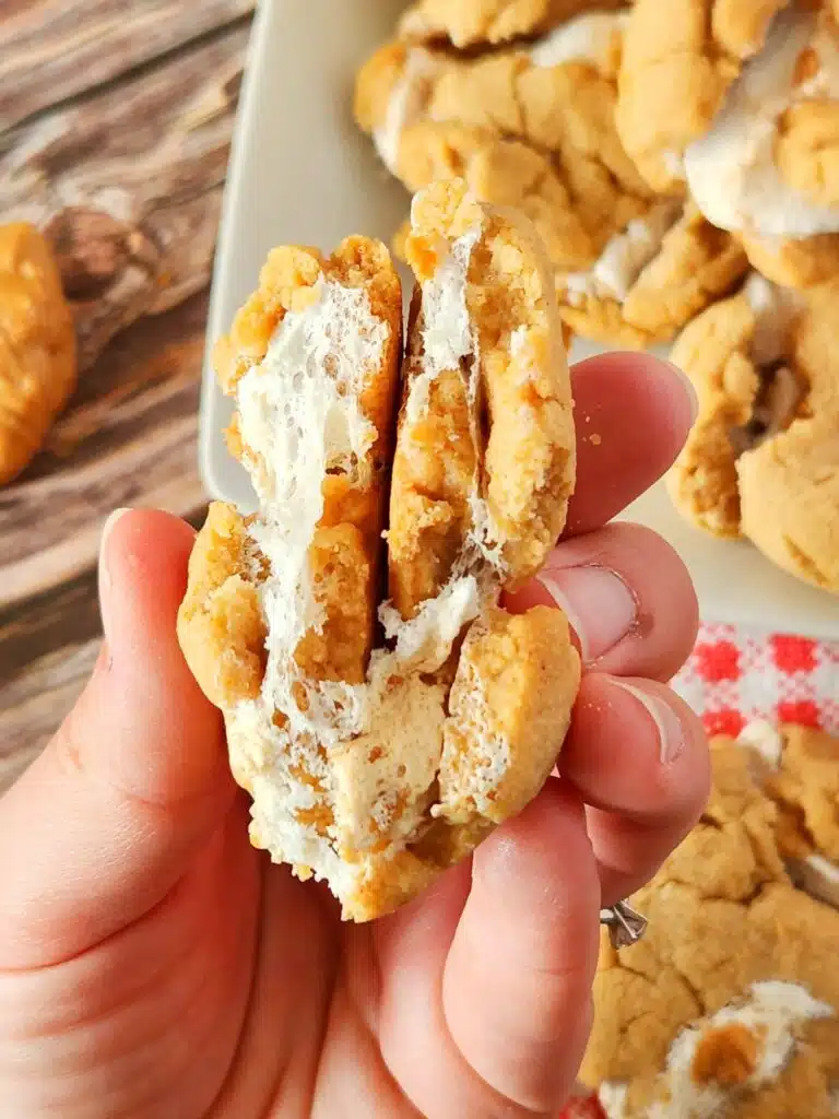 A hand holding a cookie with cream cheese filling.