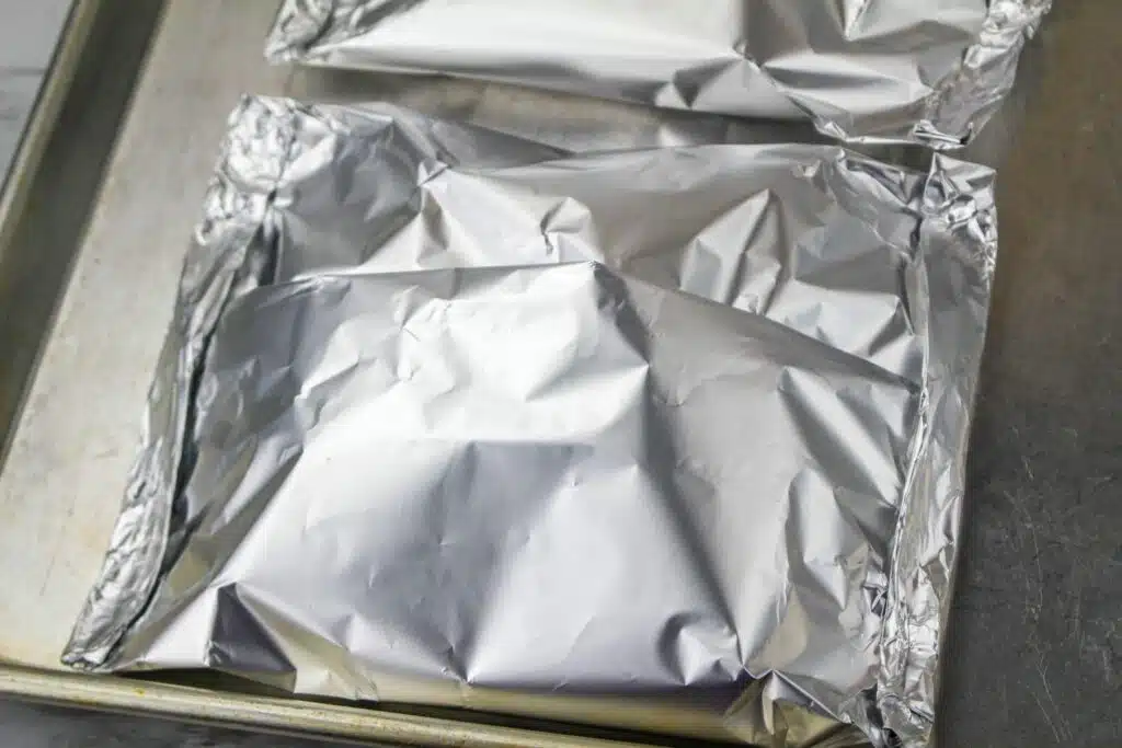 Two foil packets on a baking sheet.