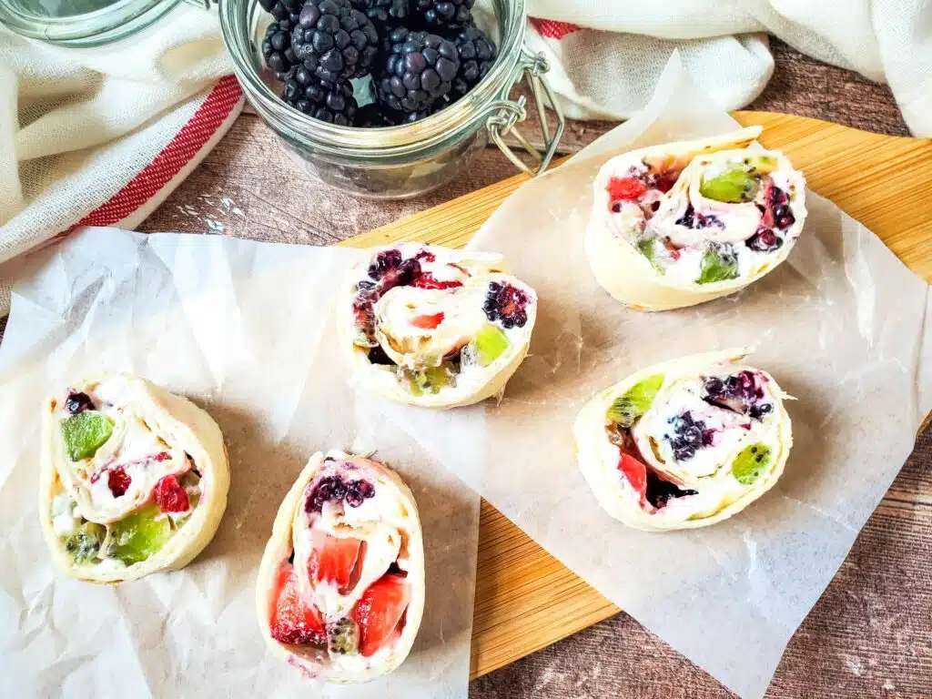 Four fruit and berry rolls on a cutting board.