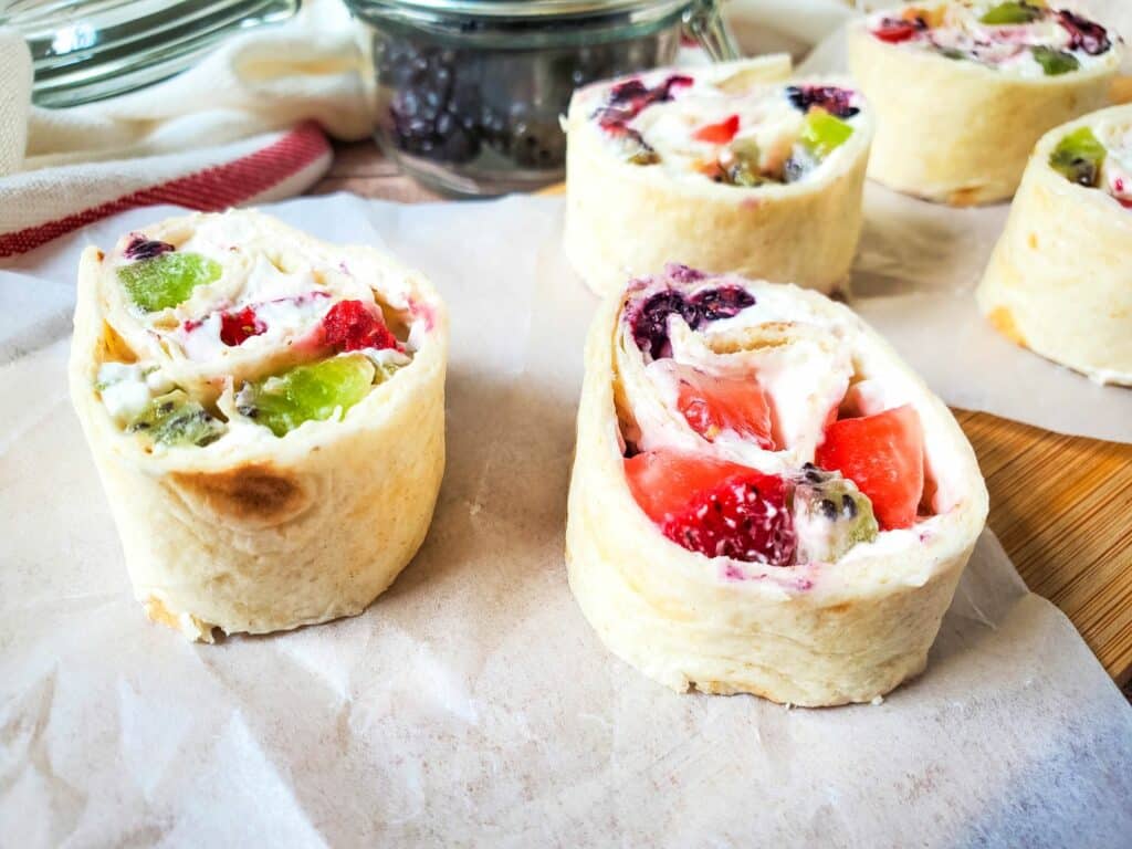 A tray of fruit and cheese wraps on top of a piece of paper.