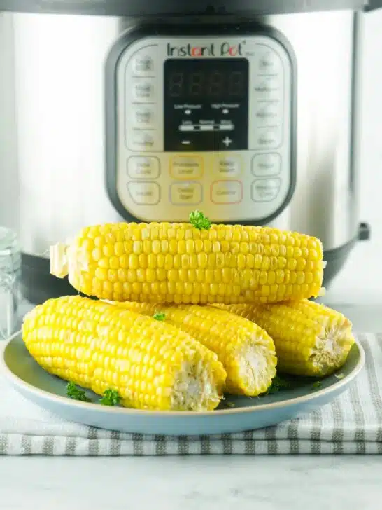 corn on the cob on a plate in front of an Instant Pot