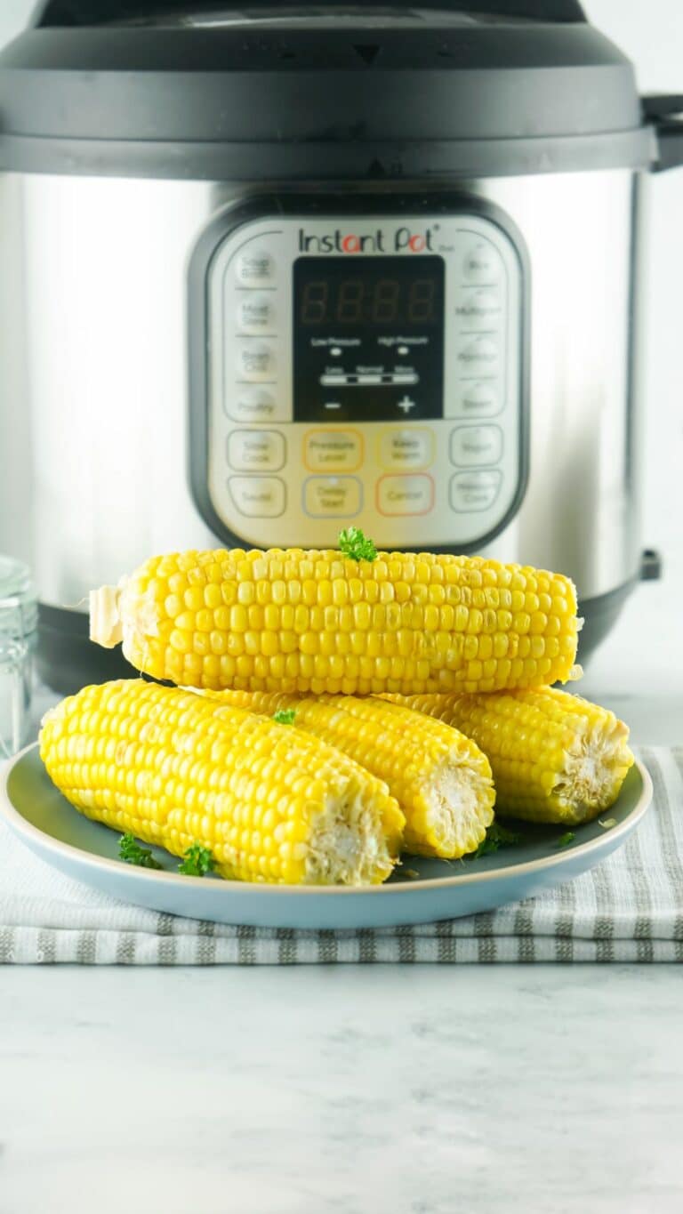 corn on the cob on a plate in front of an Instant Pot