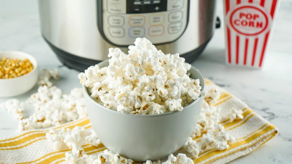 A bowl of popcorn in front of an instant pot.