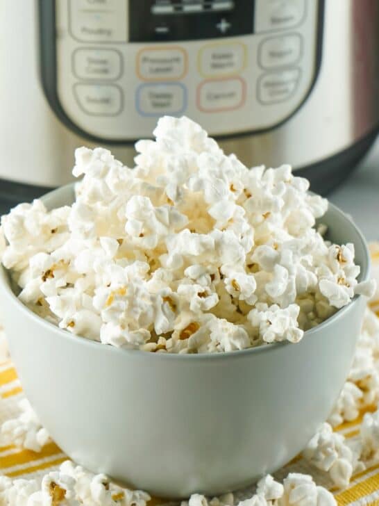 A bowl of popcorn in front of an instant pot.