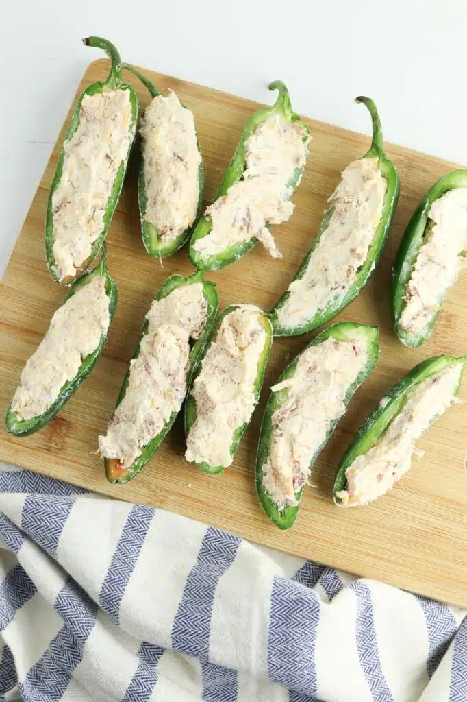 Stuffed jalapenos on a wooden cutting board.