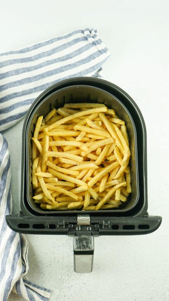 French fries in an air fryer on a white background.