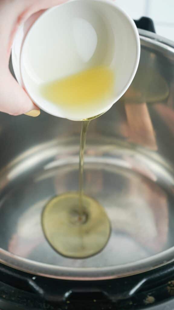 A person pouring oil into a bowl on a stove.