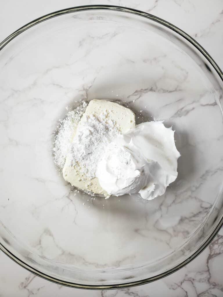 Whipped cream and powdered sugar in a glass bowl.