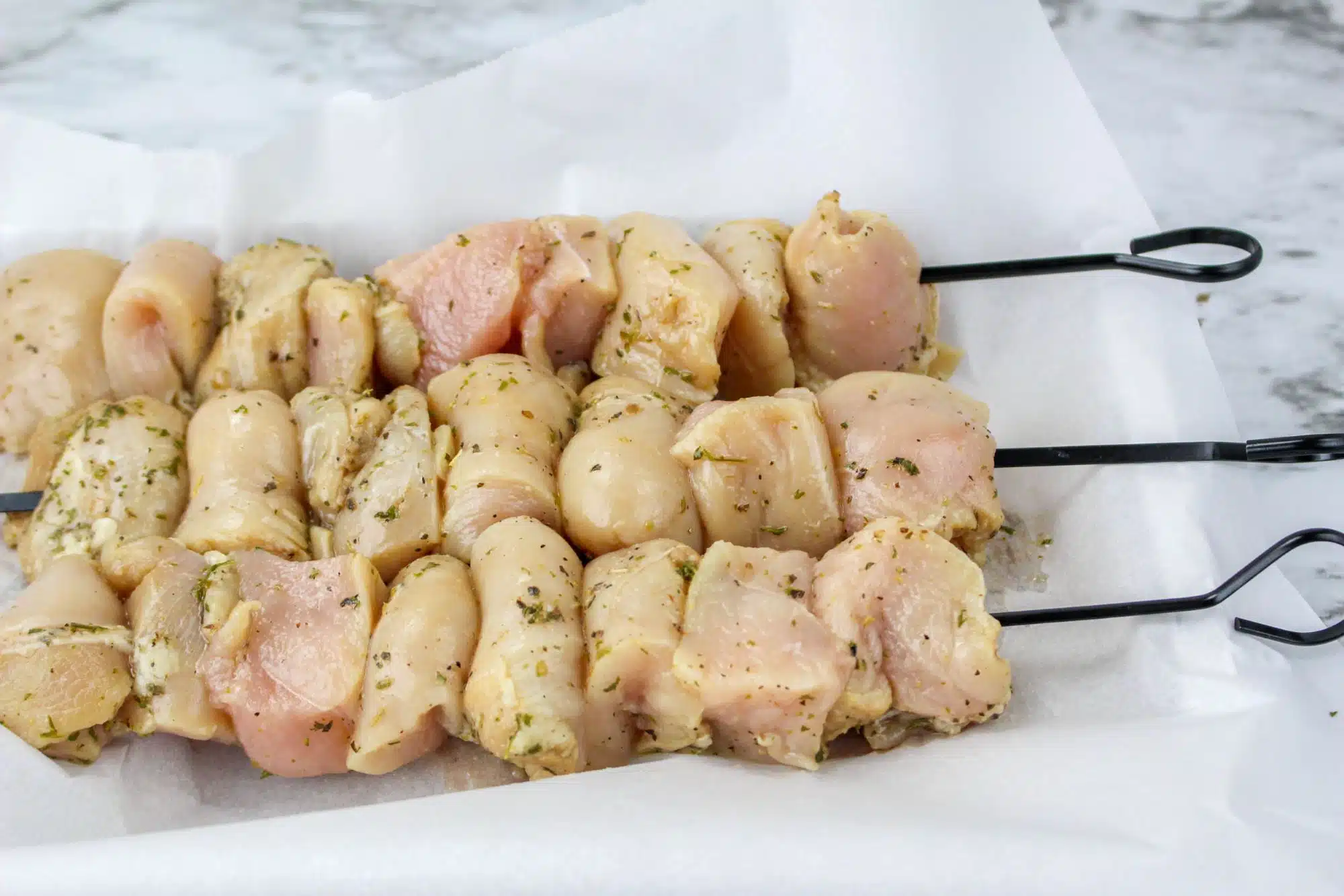 Chicken skewers on a white paper.