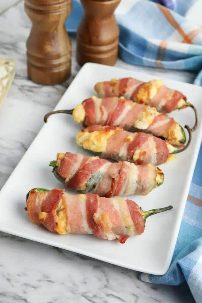 Bacon wrapped jalapenos on a white plate.