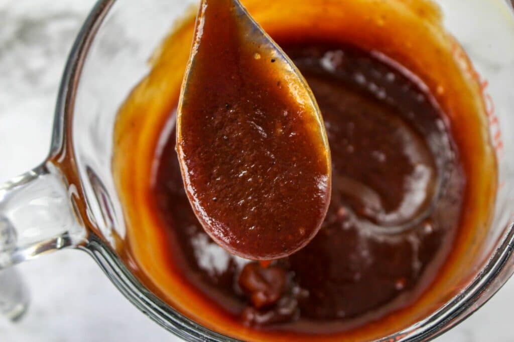 A spoonful of bbq sauce in a glass bowl.