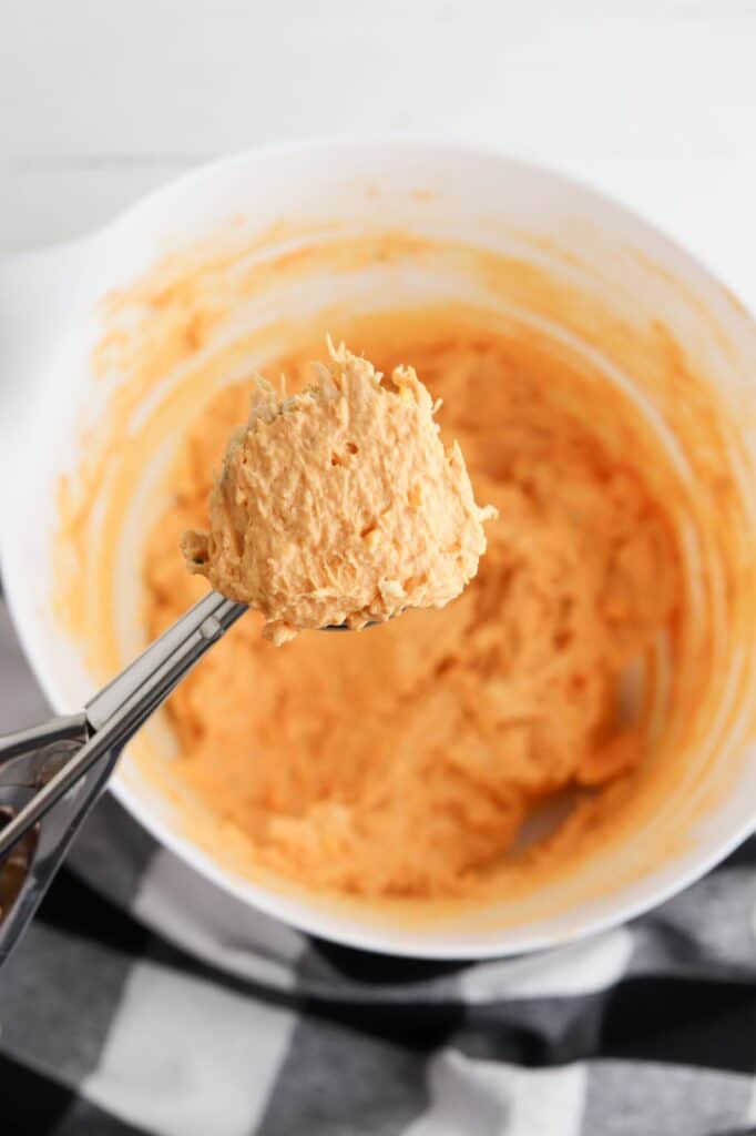 A spoon is being used to stir a bowl of mashed potatoes.