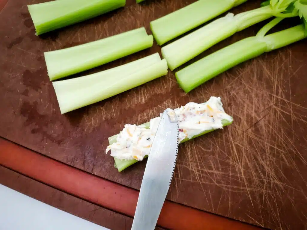 Celery sticks with a knife on a cutting board.