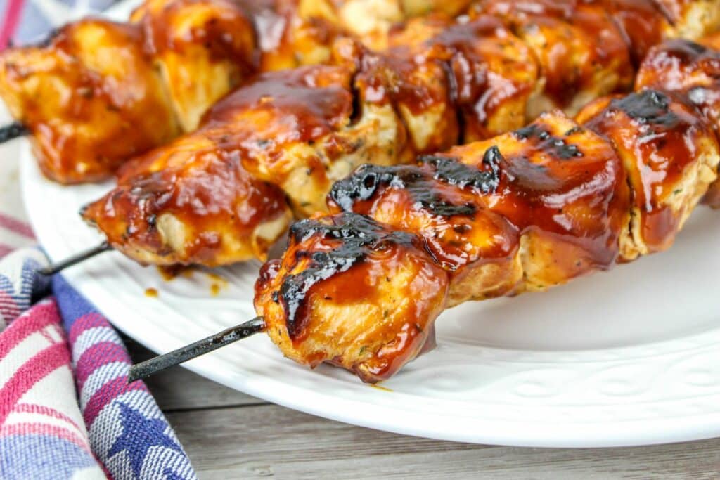 Bbq chicken skewers on a white plate.