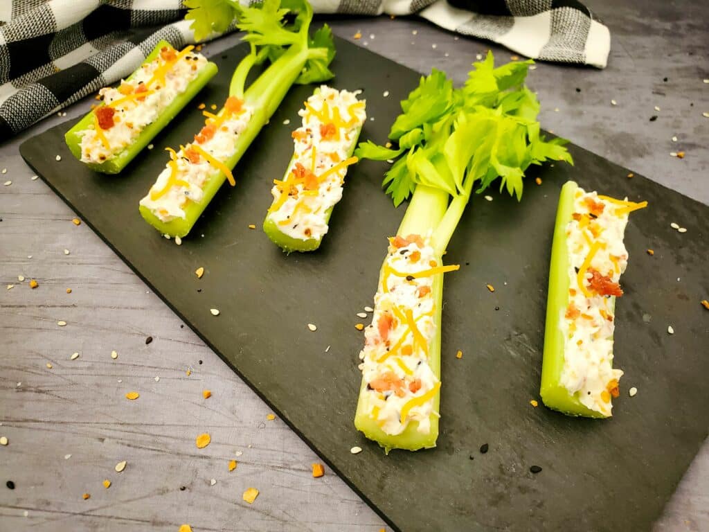 Celery sticks with cream cheese and chives on a plate.